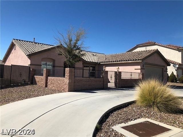 1083 Sterling Peak St, Las Vegas, NV 89110 - mediterranean / spanish home featuring a garage, stucco siding, a fenced front yard, driveway, and a tiled roof