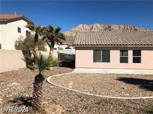 1083 Sterling Peak St, Las Vegas, NV 89110 - back of house featuring a tile roof, fence, a mountain view, and stucco siding