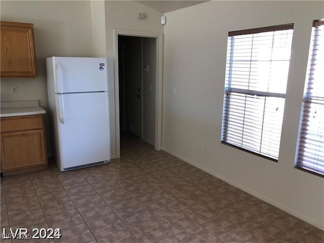 1083 Sterling Peak St, Las Vegas, NV 89110 - kitchen with freestanding refrigerator, brown cabinetry, light countertops, and baseboards