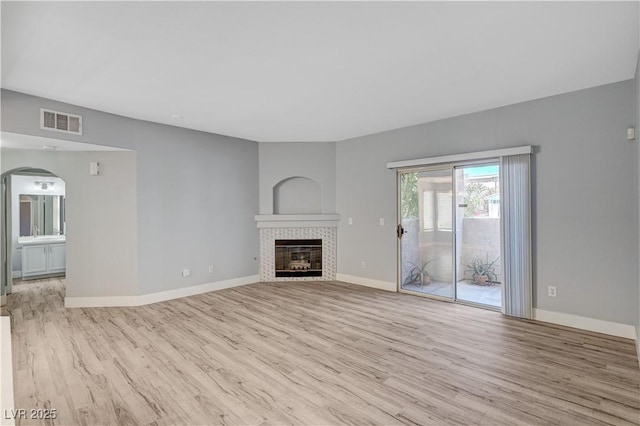 1501 Oscar Ct Unit 101, Las Vegas, NV 89146 - unfurnished living room with wood finished floors, a tile fireplace, baseboards, and arched walkways