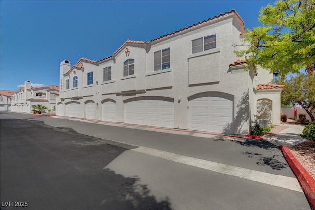 1501 Oscar Ct Unit 101, Las Vegas, NV 89146 - mediterranean / spanish-style house featuring a tile roof, stucco siding, a garage, and central AC