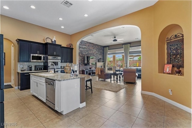 7719 Villa Montara St, Las Vegas, NV 89123 - kitchen with stainless steel appliances, arched walkways, ceiling fan, a sink, and light tile patterned floors