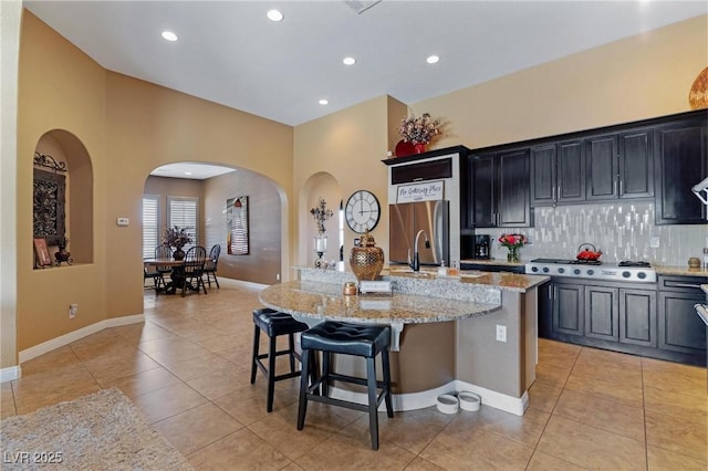 7719 Villa Montara St, Las Vegas, NV 89123 - kitchen with arched walkways, light tile patterned flooring, a kitchen island with sink, a breakfast bar, and recessed lighting