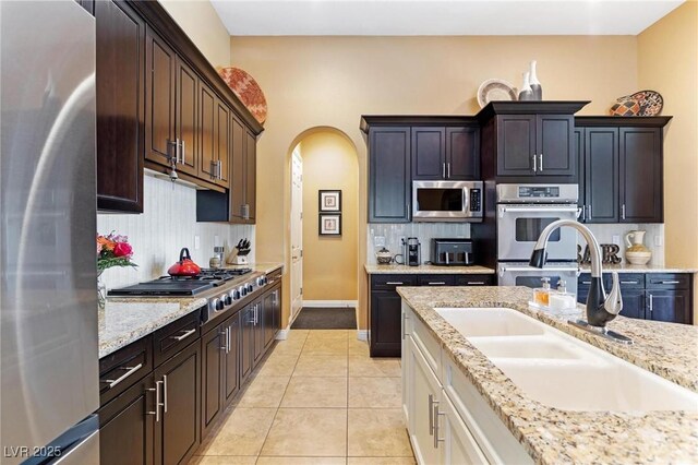 7719 Villa Montara St, Las Vegas, NV 89123 - kitchen with appliances with stainless steel finishes, a sink, arched walkways, backsplash, and light tile patterned flooring