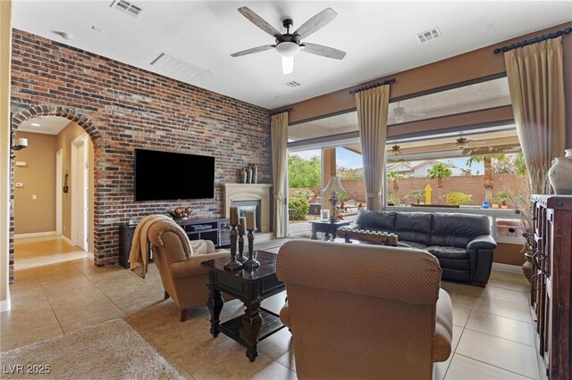 7719 Villa Montara St, Las Vegas, NV 89123 - living area featuring a ceiling fan, light tile patterned floors, a fireplace, arched walkways, and brick wall