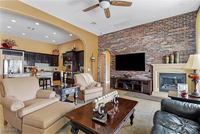 7719 Villa Montara St, Las Vegas, NV 89123 - living room with arched walkways, a ceiling fan, light tile patterned flooring, recessed lighting, and brick wall