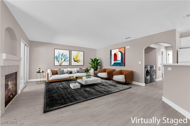 4324 W Lake Mead Blvd Unit 202, Las Vegas, NV 89108 - living room featuring washing machine and clothes dryer, light wood-style flooring, a fireplace, and arched walkways