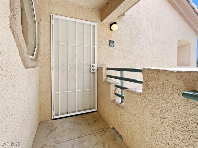 doorway to property featuring stucco siding and a balcony