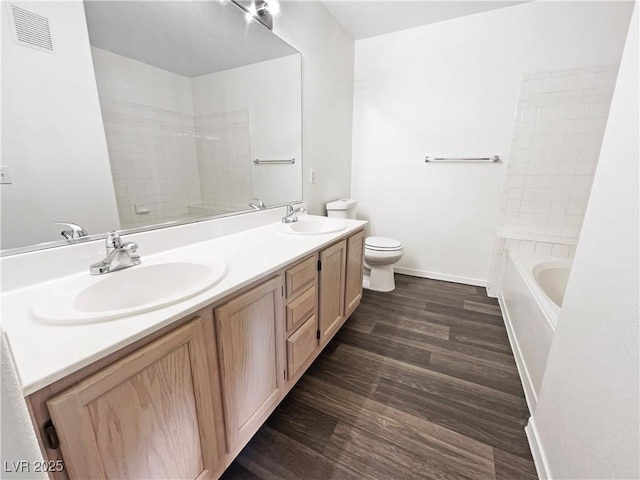 full bath with toilet, wood finished floors, double vanity, and baseboards