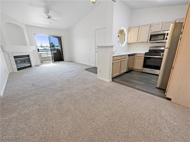 kitchen featuring appliances with stainless steel finishes, open floor plan, dark colored carpet, light brown cabinetry, and baseboards