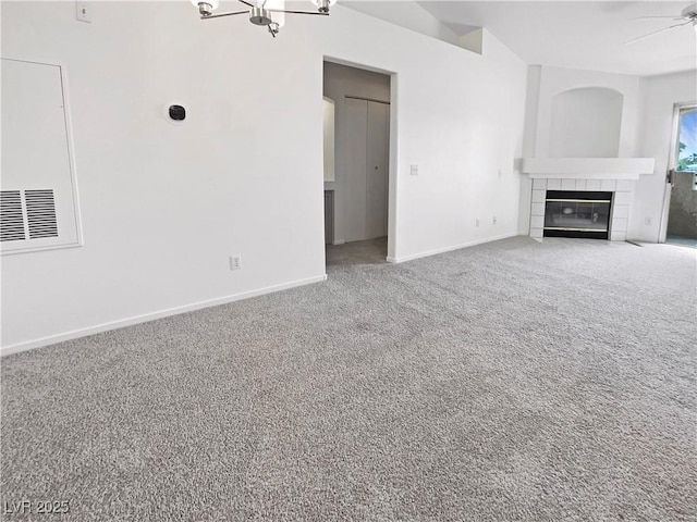 unfurnished living room with carpet, baseboards, a fireplace, ceiling fan, and a chandelier
