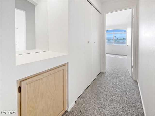 hall featuring light carpet and baseboards