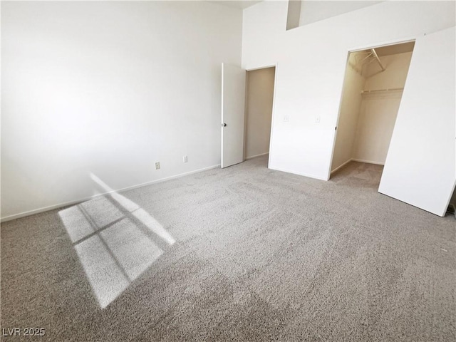unfurnished bedroom with carpet, a walk in closet, baseboards, and a closet