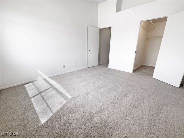unfurnished bedroom featuring carpet, a walk in closet, and baseboards
