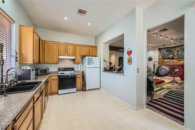 10310 Songsparrow Ct, Las Vegas, NV 89135 - kitchen featuring gas range, freestanding refrigerator, light floors, a sink, and light countertops