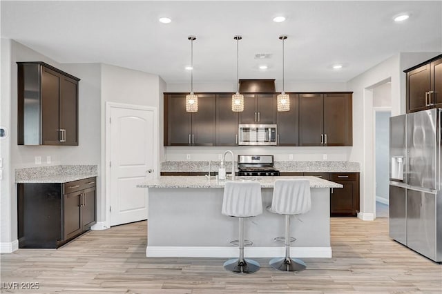 kitchen featuring appliances with stainless steel finishes, dark brown cabinetry, light wood finished floors, baseboards, and recessed lighting