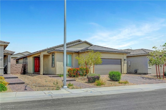 view of front of home featuring an attached garage, driveway, stucco siding, and a tile roof