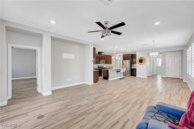 unfurnished living room with a ceiling fan, a chandelier, baseboards, light wood-style floors, and recessed lighting