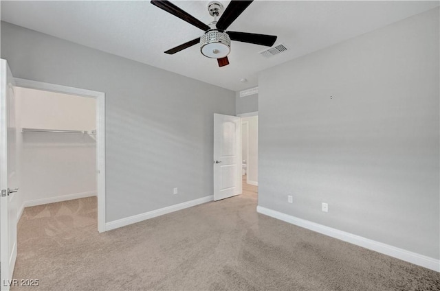 unfurnished bedroom featuring carpet, a spacious closet, baseboards, ceiling fan, and a closet
