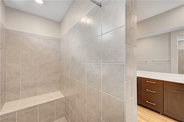 bathroom with vanity, tiled shower, recessed lighting, and wood finished floors