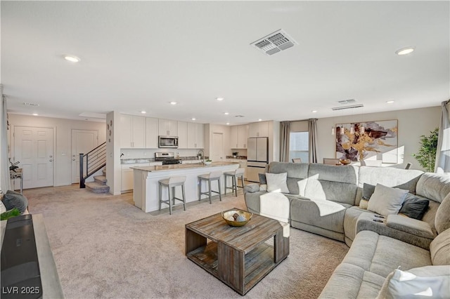 living area featuring recessed lighting, light colored carpet, and stairs