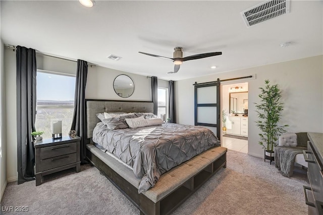 carpeted bedroom with a barn door, ensuite bathroom, recessed lighting, and a ceiling fan
