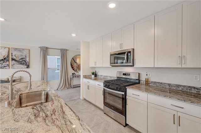 kitchen with stainless steel appliances, a sink, white cabinetry, light stone countertops, and recessed lighting