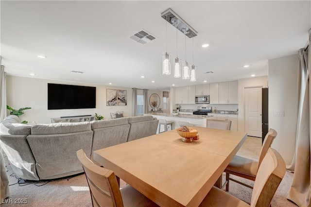 dining room with recessed lighting and light carpet