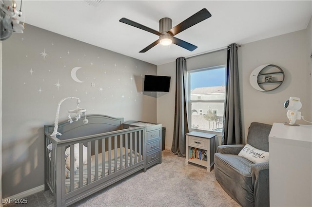 bedroom featuring light colored carpet, a crib, and a ceiling fan
