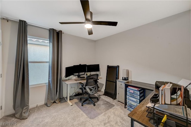home office featuring light colored carpet, a ceiling fan, and baseboards