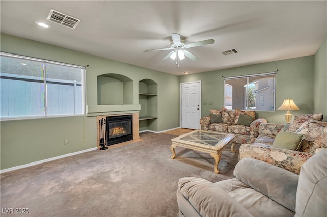 9165 Starling Wing Pl, Las Vegas, NV 89143 - carpeted living area with built in shelves, a ceiling fan, baseboards, and a fireplace with flush hearth