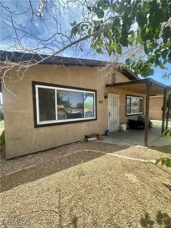view of front of house featuring stucco siding and a patio