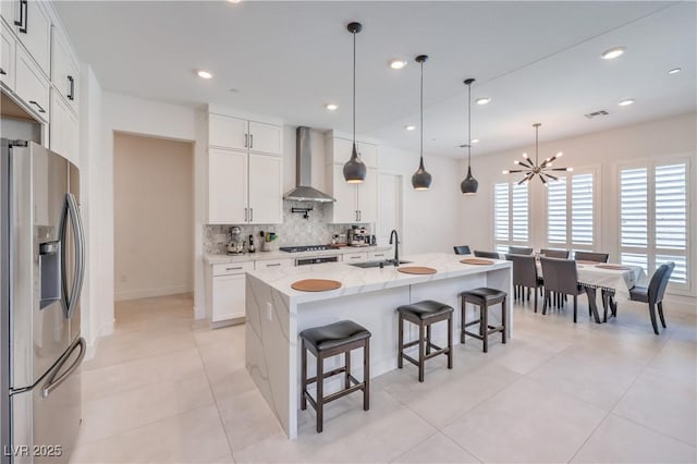 201 Carmel Sky St, Las Vegas, NV 89138 - kitchen featuring stainless steel refrigerator with ice dispenser, wall chimney range hood, a chandelier, backsplash, and a breakfast bar area