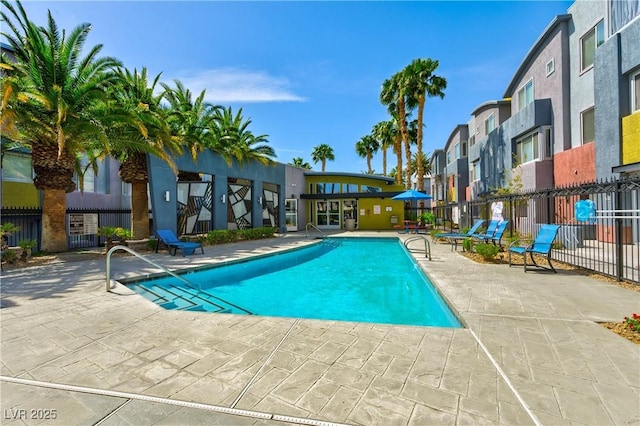 community pool with a patio area, fence, and a residential view