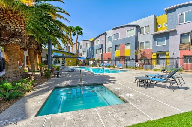 community pool featuring a residential view, fence, a patio, and a hot tub