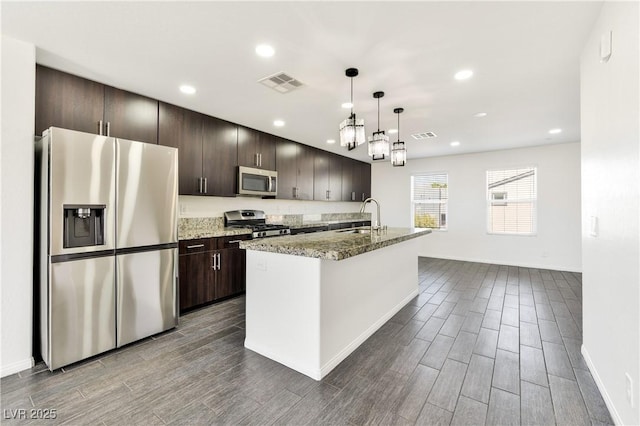 kitchen featuring stainless steel appliances, a sink, wood finish floors, dark brown cabinets, and recessed lighting