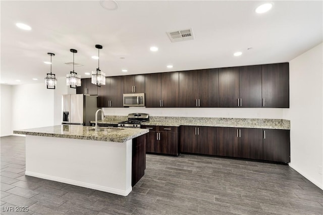 kitchen with stainless steel appliances, a sink, recessed lighting, dark brown cabinetry, and light stone countertops