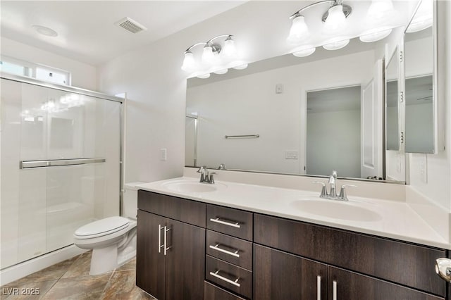 bathroom featuring a stall shower, toilet, and double vanity