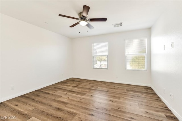 unfurnished room with wood finished floors, a ceiling fan, and baseboards