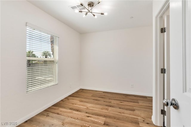 unfurnished room with a chandelier, wood finished floors, and baseboards