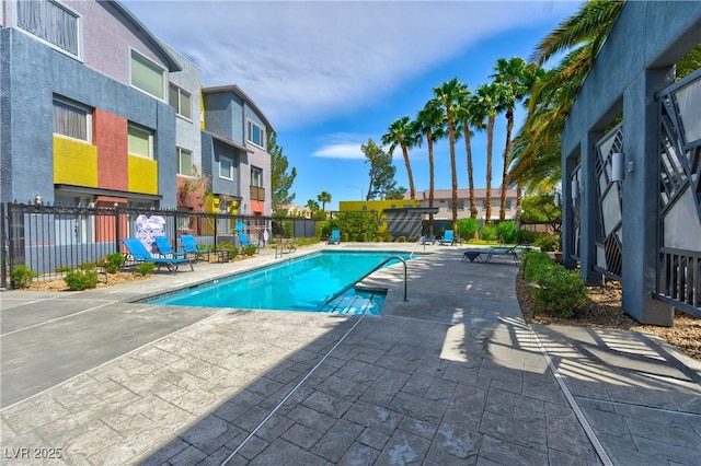 community pool featuring fence, a patio area, and a residential view