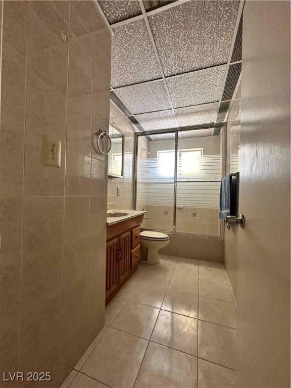 2300 Pardee Pl, Las Vegas, NV 89104 - bathroom with toilet, tile walls, vanity, shower / bath combination with glass door, and tile patterned flooring