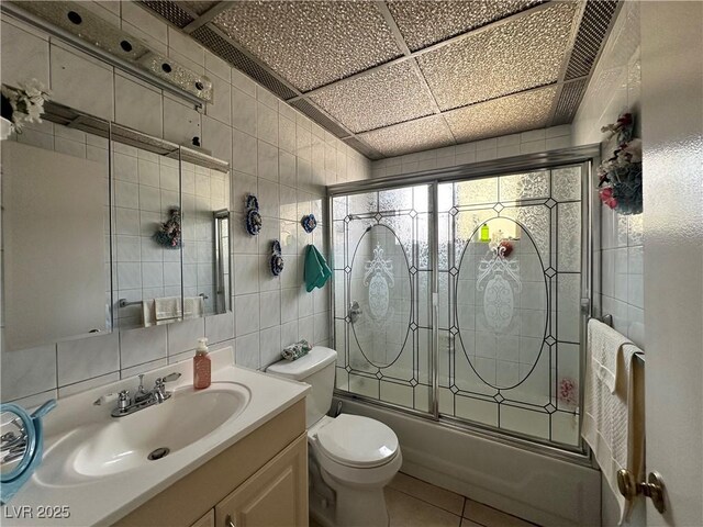2300 Pardee Pl, Las Vegas, NV 89104 - full bathroom featuring tile walls, combined bath / shower with glass door, vanity, toilet, and tile patterned flooring