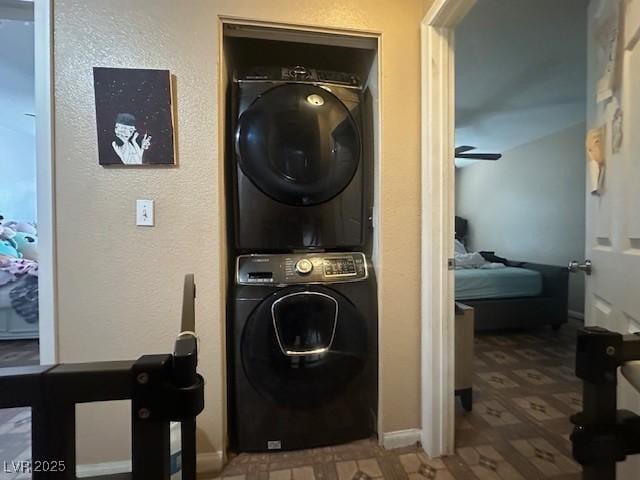 laundry room with stacked washer and clothes dryer, baseboards, and tile patterned floors