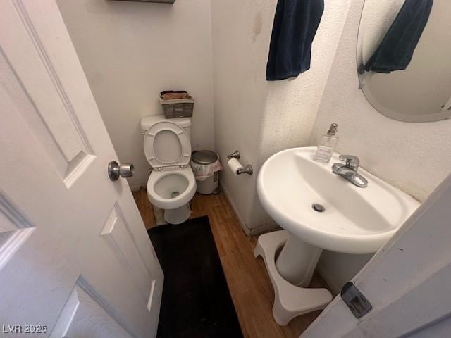 bathroom featuring toilet, wood finished floors, and a sink