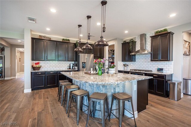 3698 Regatta Landing Dr, Las Vegas, NV 89141 - kitchen with wall chimney range hood, high end fridge, a kitchen breakfast bar, light stone counters, and an island with sink