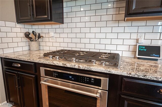 3698 Regatta Landing Dr, Las Vegas, NV 89141 - kitchen featuring stainless steel appliances, dark brown cabinetry, tasteful backsplash, and light stone counters