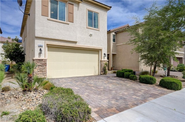 view of front of property featuring an attached garage, stucco siding, stone siding, and driveway