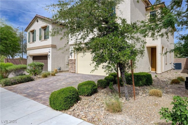view of front of home with stucco siding, driveway, a garage, and central AC unit