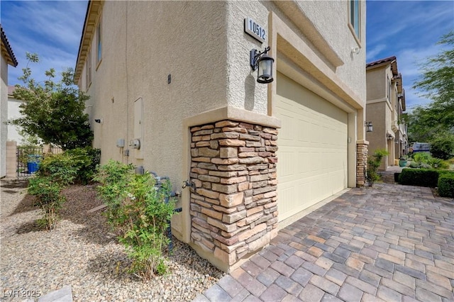 view of side of property featuring stucco siding, stone siding, and driveway